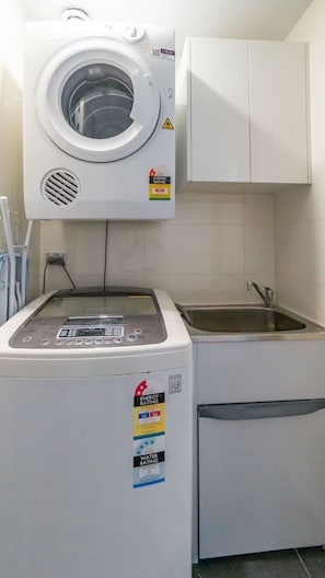 A laundry room with a front-loading washing machine and a sink. - City and Park View Close to Station 1 Car Space (Beaconsfield)