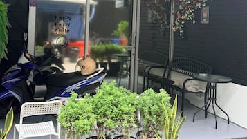 A property management company sign, a scooter, potted plants, and outdoor seating.