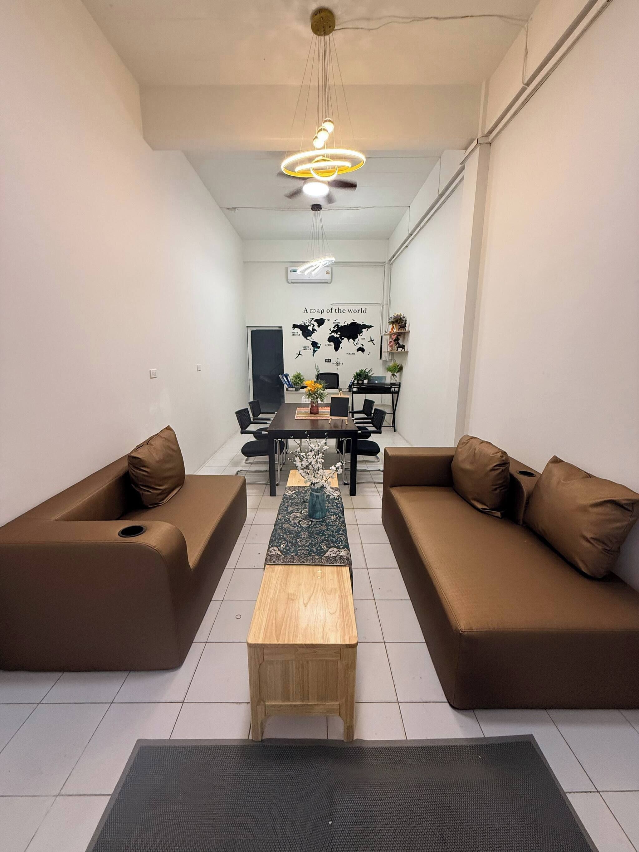 A modern living room with a central coffee table, two sofas, a dining table with chairs, and a world map on the wall.