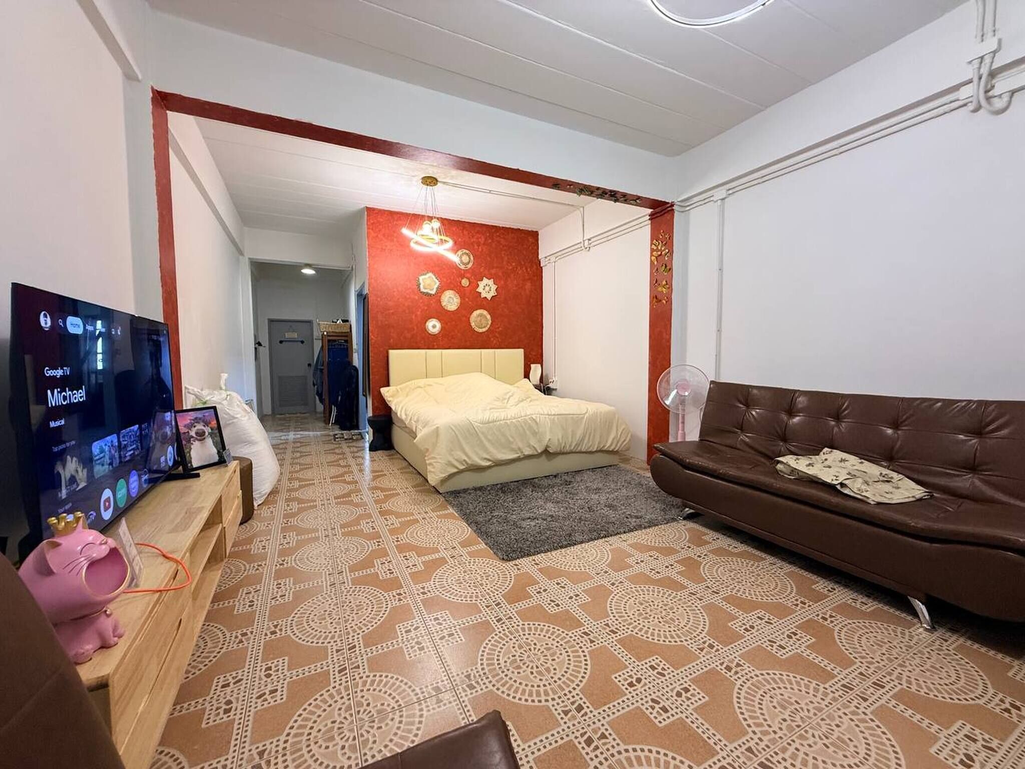 A modern bedroom with a bed, a TV, and a brown leather sofa.
