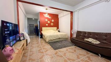 A modern bedroom with a bed, a TV, and a brown leather sofa.