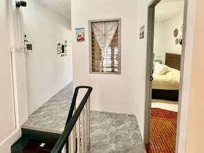 A hallway with a marble floor, a window with a curtain, and a bed with a white pillow in the adjacent room. - Full Private House in Heart of Pattaya, 2 min to Beach (Pattaya)
