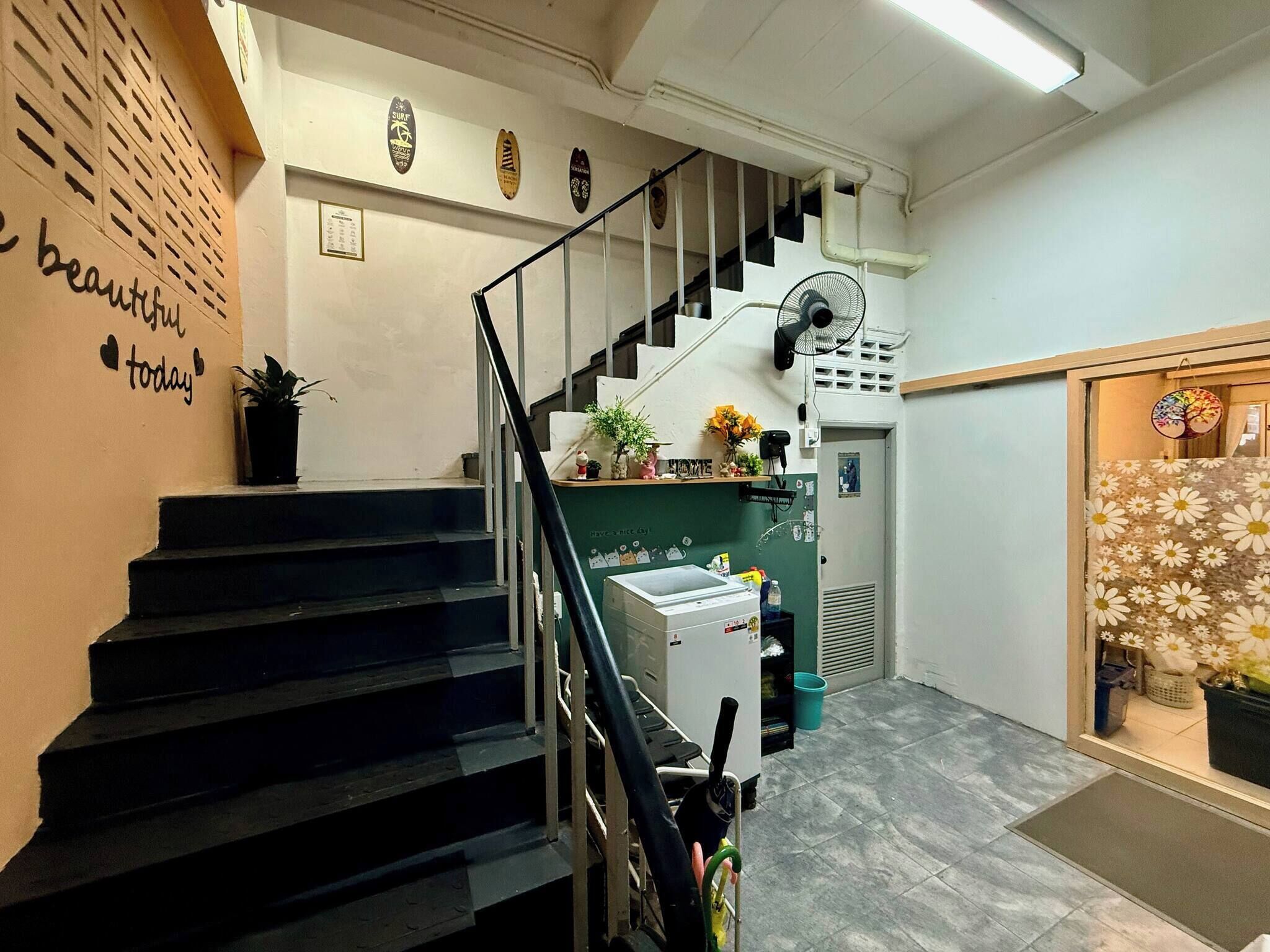 A staircase leading to a landing with a wall-mounted fan, a small plant, and a sign with a heart symbol.