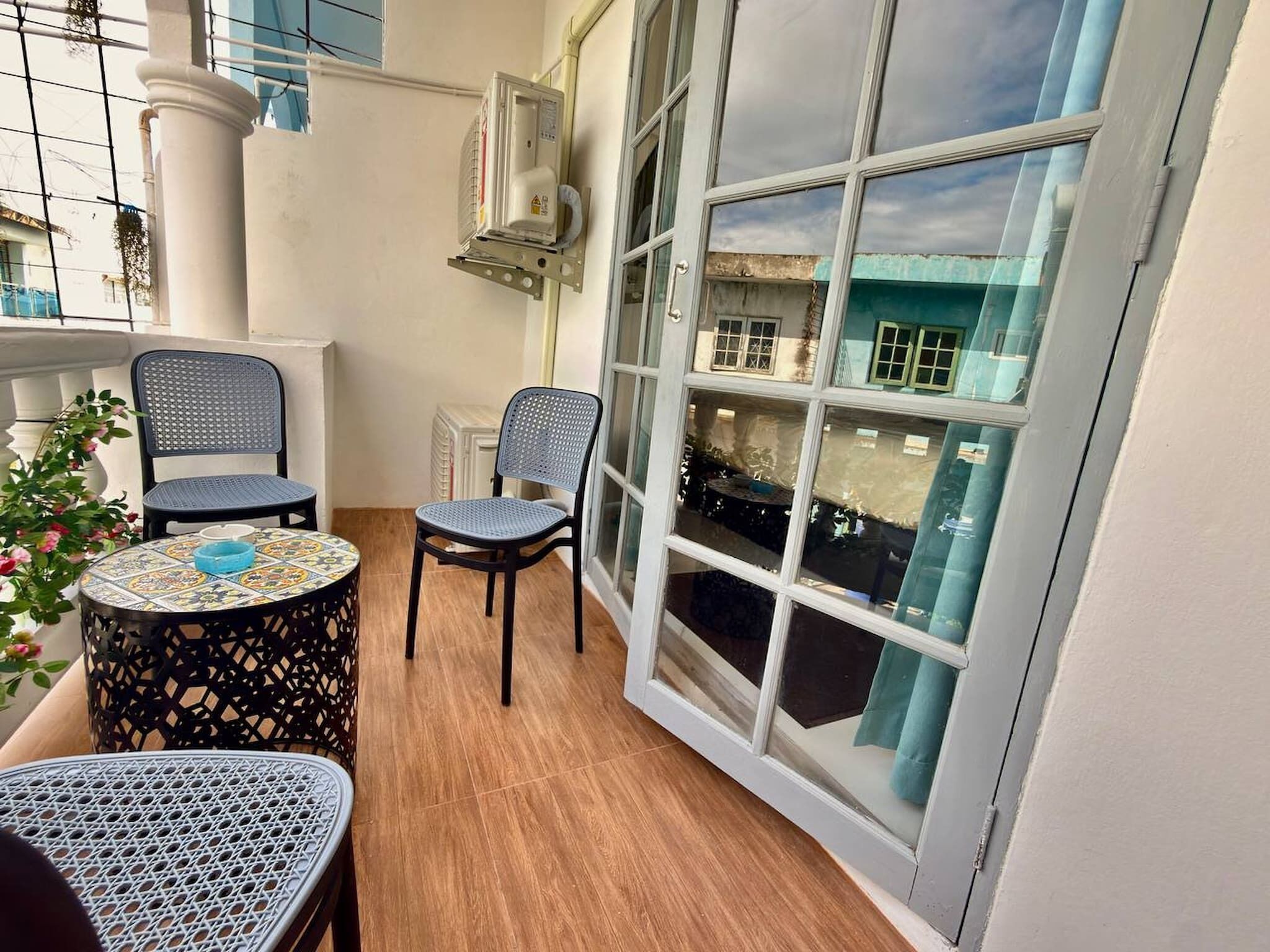 En balkon med to stole, et lille bord og en potteplante.
