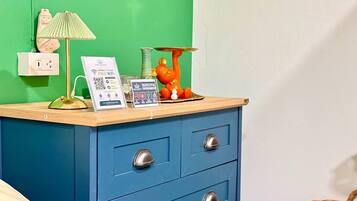 A blue chest of drawers with a lamp, a teddy bear, and a sign offering free WiFi.