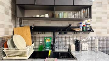 A kitchen with a dish rack, dish soap, a sponge, and a coffee maker.