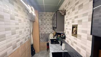 A compact kitchen with white and gray tiles, a small countertop, and a hanging light fixture.