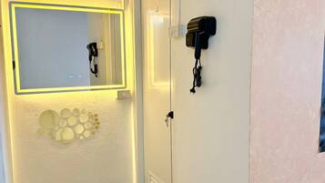 A room with a mirror, a wall-mounted hairdryer, and a door with a handle.