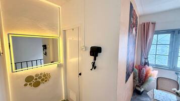 A hallway with a mirror, a door, a wall-mounted phone, and a window with curtains.