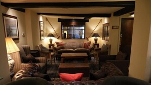 A cozy living room with a fireplace, comfortable seating, and a view through a window. - Hotel Manor - Datchet, Windsor (Slough)
