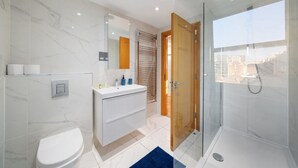 Et moderne badeværelse med toilet, håndvask og bruser.