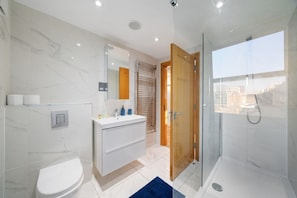 Ein modernes Badezimmer mit Toilette, Waschtisch und Dusche.