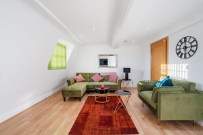 Ein modernes Wohnzimmer mit einem Ecksofa, einem kleinen runden Tisch und einem roten Teppich.