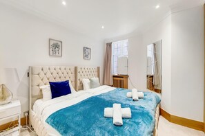 Ein Hotelzimmer mit einem großen Bett, einem Nachttisch, einem Spiegel und zwei gerahmten Bildern an der Wand.