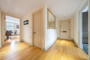A hallway with wooden flooring, white doors, and a large mirror. - Luxurious 2 Bedroom in Mayfair (London)