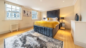 A bedroom with a large bed, a radiator, a window, and a nightstand. - Luxurious 2 Bedroom in Mayfair (London)
