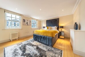 A bedroom with a large bed, a radiator, a window, and a nightstand. - Luxurious 2 Bedroom in Mayfair (London)