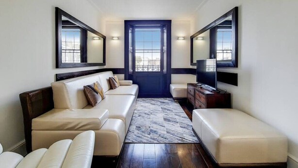 A modern living room with a sofa, ottoman, and a television. - Superior One Bedroom Apartment in Belgravia (London)