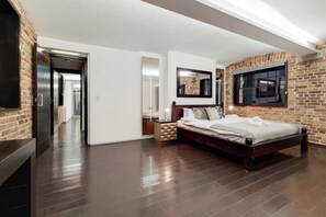 A bedroom with a brick wall, a bed, a nightstand, a mirror, and a window. - Amazing 2 Bedroom Apartment in Belgravia (London)