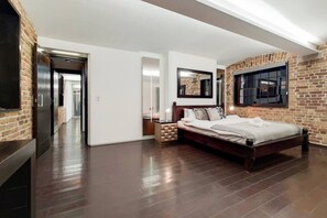 Ein Schlafzimmer mit Ziegelwand, einem Bett, einem Nachttisch, einem Spiegel und einem Fenster.