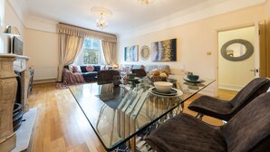 A spacious living room with a glass dining table, comfortable seating, and decorative wall art. - Deluxe 2 Bedroom Apartment In An Amazing Location (London)