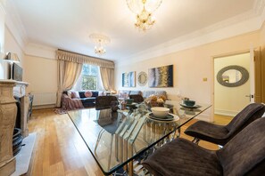 A spacious living room with a glass dining table, comfortable seating, and decorative wall art. - Deluxe 2 Bedroom Apartment In An Amazing Location (London)