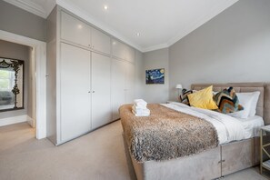 A bedroom with a bed, a wardrobe, a painting, and a window with a view. - Chic Spacious 2 Bedroom Duplex (London)