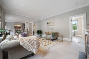 A spacious living room with a sofa, coffee table, and artwork on the walls. - Chic Spacious 2 Bedroom Duplex (London)