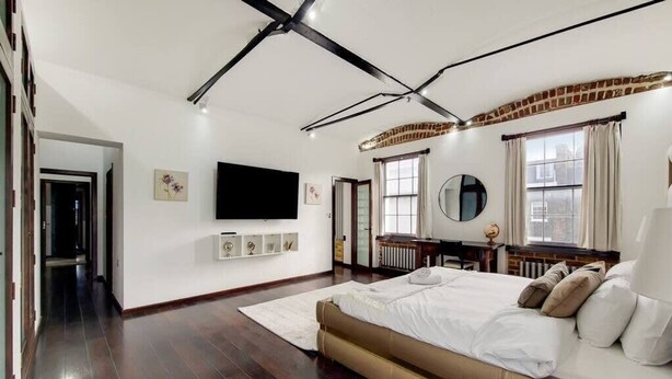 Ein modernes Schlafzimmer mit einem großen Bett, einem Flachbildfernseher und einem Kamin.