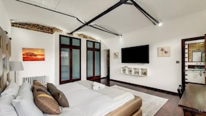 Ein modernes Schlafzimmer mit einem großen Bett, einem Flachbildfernseher und einem Kamin.