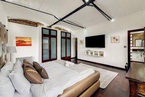 Ein modernes Schlafzimmer mit einem großen Bett, einem Flachbildfernseher und einem Kamin.