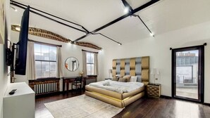 Ein modernes Schlafzimmer mit einem großen Bett, einem Schreibtisch und Blick auf die Stadt durch das Fenster.