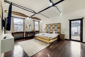 Ein modernes Schlafzimmer mit einem großen Bett, einem Schreibtisch und Blick auf die Stadt durch das Fenster.