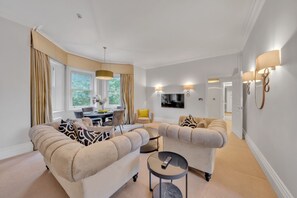 Uma sala de estar moderna com dois sofás, uma mesa de jantar e uma televisão.