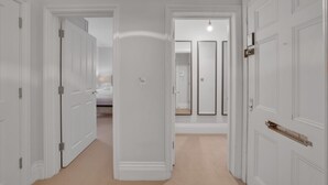 Ein Flur mit weißen Türen, einem Bett und einem Spiegel.