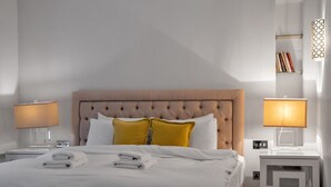 Ein Hotelzimmer mit einem großen Bett, zwei Nachttischlampen, einem Nachttisch und einem Beistelltisch.