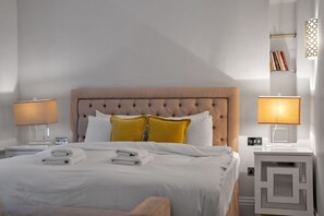 Quarto de hotel com uma cama grande, duas luminárias de cabeceira, uma mesa de cabeceira e um criado-mudo.