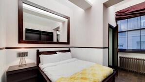 A bedroom with a bed, a nightstand, a mirror, and a window with a view. - Magnificent 2 Bedroom Apartment In Belgravia (London)