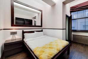 A bedroom with a bed, a nightstand, a mirror, and a window with a view. - Magnificent 2 Bedroom Apartment In Belgravia (London)