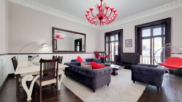 A modern living room with a dining area, a large mirror, and a red chandelier. - Magnificent 2 Bedroom Apartment In Belgravia (London)