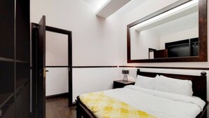 A hotel room with a bed, a nightstand, a mirror, and a door. - Magnificent 2 Bedroom Apartment In Belgravia (London)