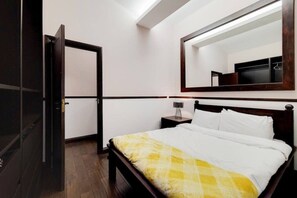 A hotel room with a bed, a nightstand, a mirror, and a door. - Magnificent 2 Bedroom Apartment In Belgravia (London)