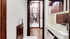 A narrow hallway with a wooden door, a white sink, and a mirror. - Magnificent 2 Bedroom Apartment In Belgravia (London)