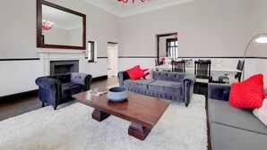 A living room with a fireplace, sofas, a coffee table, and a chandelier. - Magnificent 2 Bedroom Apartment In Belgravia (London)