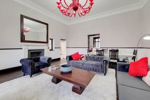 A living room with a fireplace, sofas, a coffee table, and a chandelier. - Magnificent 2 Bedroom Apartment In Belgravia (London)