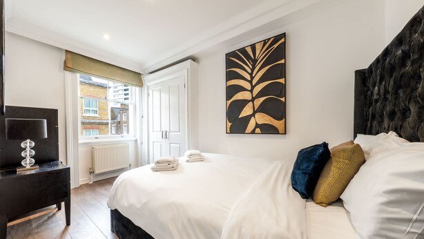 A hotel room with a bed, a desk, a radiator, and a window. - Super Deluxe 2bedroom Apartment in Mayfair (London)