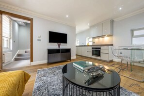 A modern living room with a flat-screen TV, a glass coffee table, and a sofa. - Sophisticated Splendor2-bedroom House in Mayfair (London)