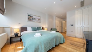 A spacious bedroom with a large bed, a painting on the wall, and a wardrobe. - Royal 4 Bedroom Apartment (London)