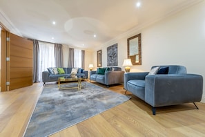 A modern living room with a sofa set, a coffee table, and a rug. - Exquisite 3-bedroom House in Mayfair (London)