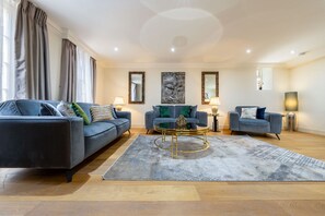 A modern living room with a blue sofa set, a coffee table, and decorative mirrors. - Exquisite 3-bedroom House in Mayfair (London)